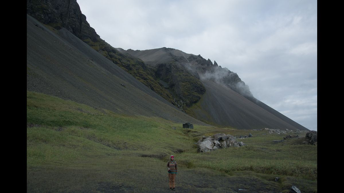 Figure in a mountainous landscape beneath a cloudy sky