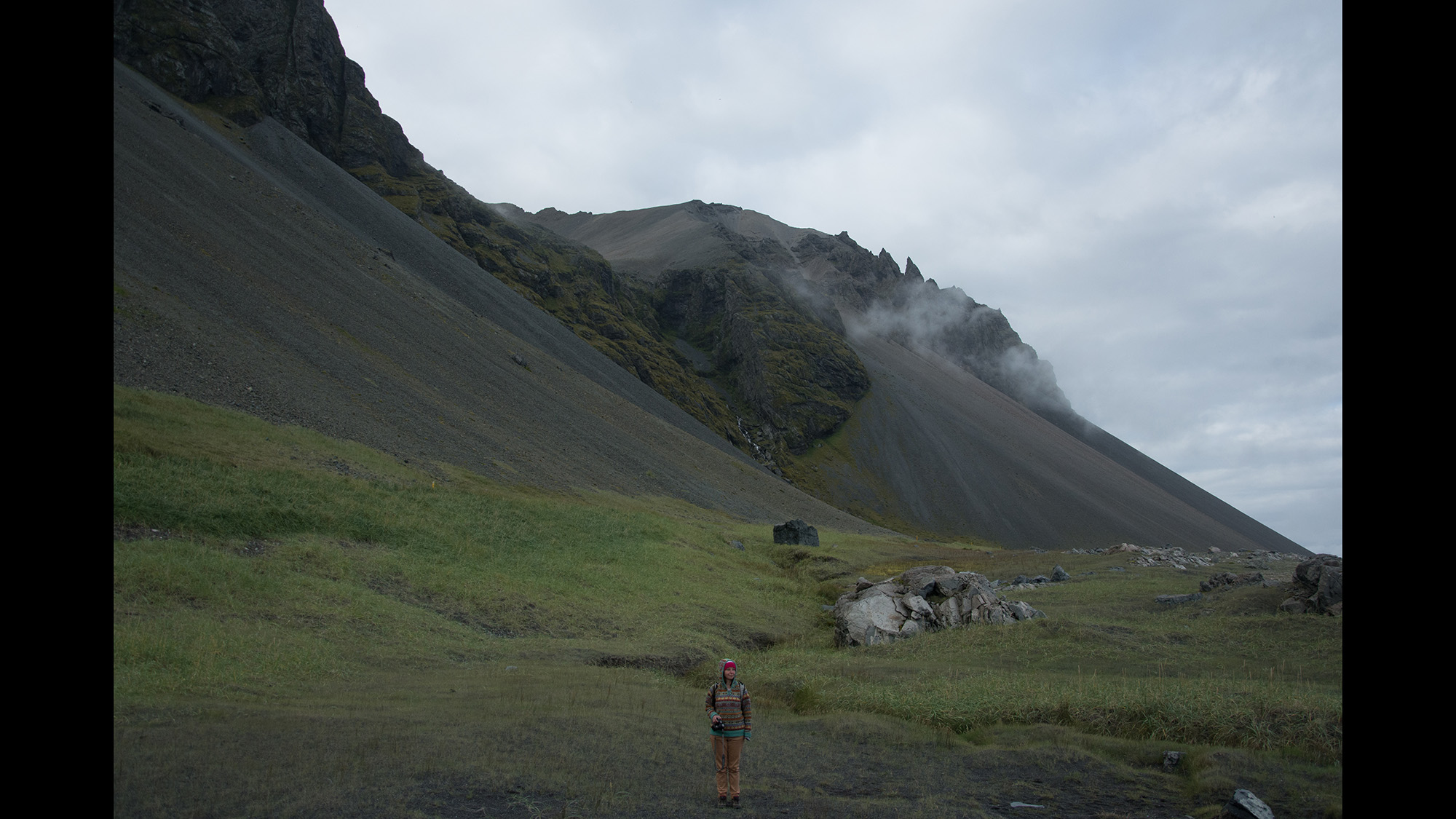 Figure in a mountainous landscape beneath a cloudy sky
