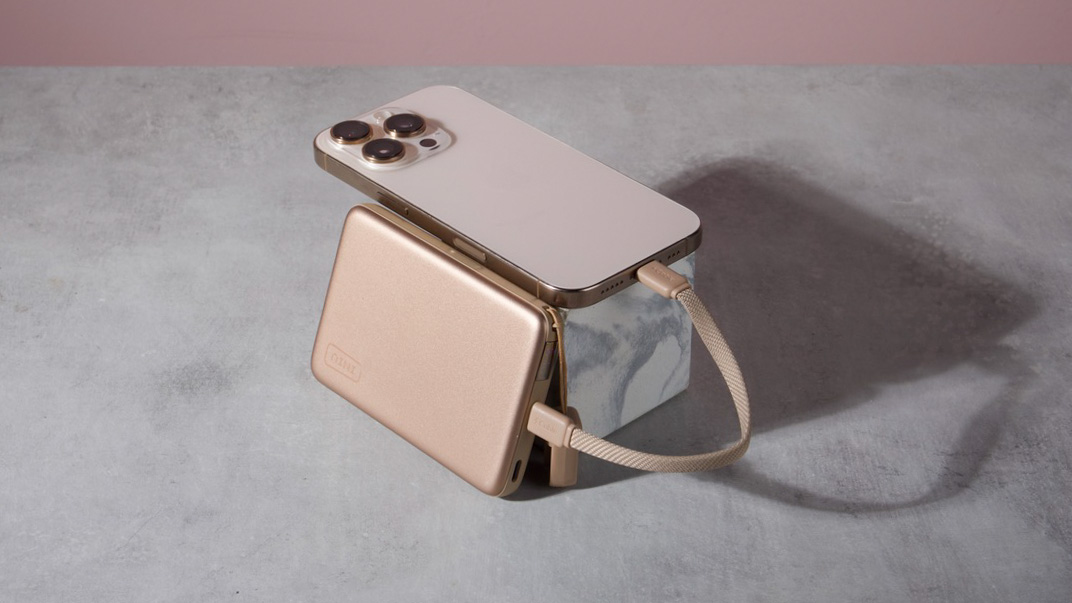 An Iniu SnapGo Air 10000mAh Power Bank leant against a marble block with an iPhone 16 Pro resting on top of it — a cable connects the two.