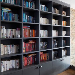 room with grey bookshelf wooden flooring and brick wall