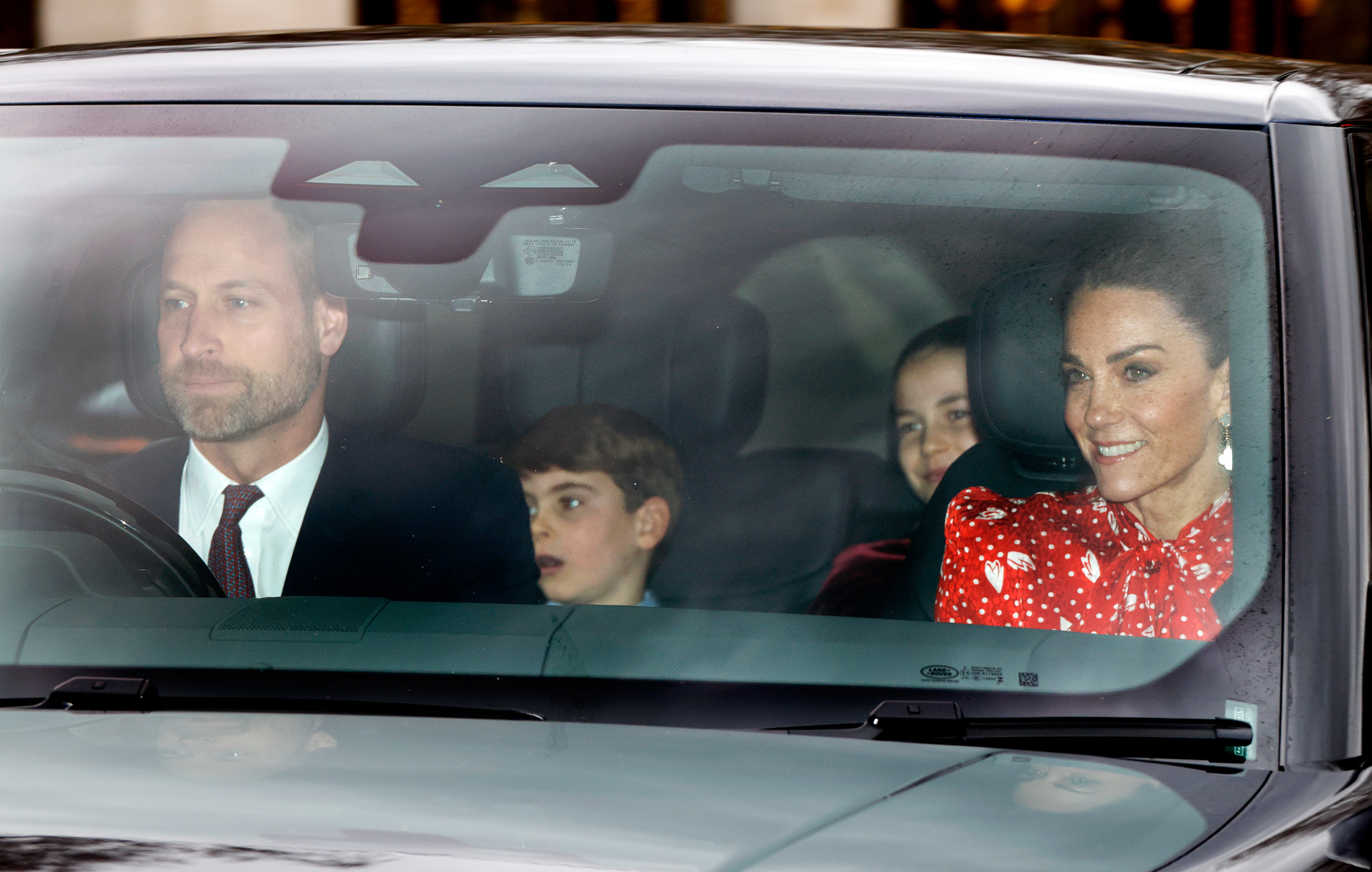 Prince William driving a car with Princess Kate, Prince Louis and Princess Charlotte riding inside