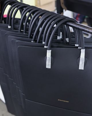 a row of strathberry bags hanging on a rack in an ubrique spain workshop