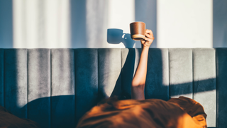 Woman holding hot drink in bed