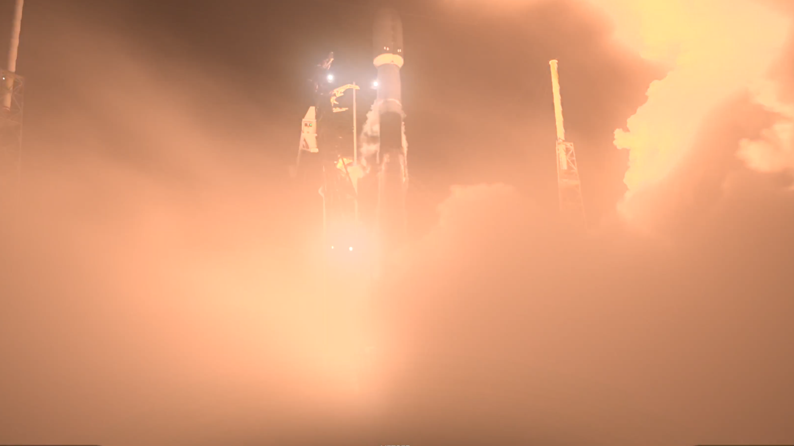 A bright smokey haze obscures all but the top of a white rocket lifting off.