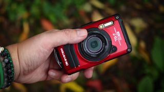 A red OM System Tough TG-7 being held in reviewer's hand