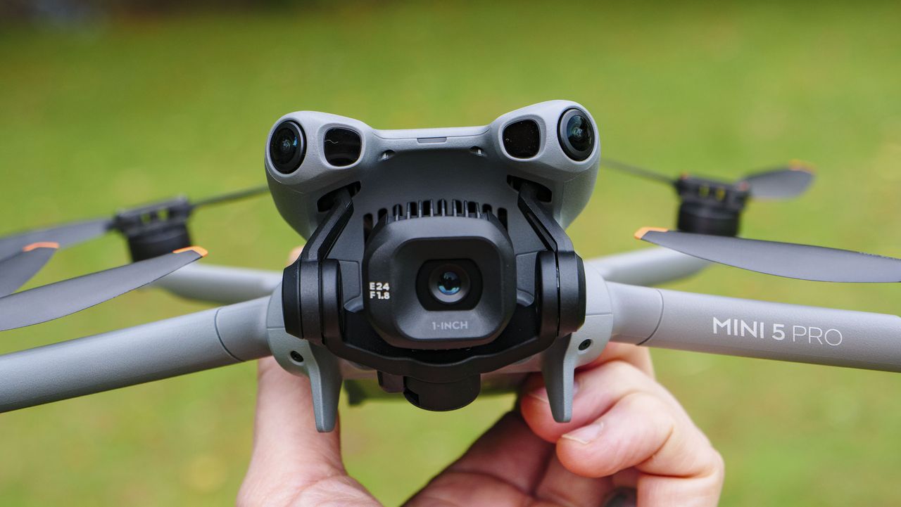 DJI Mini 5 Pro in pilot's hand, grass background