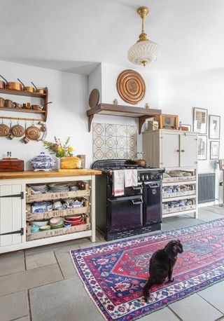 Kitchen with units incorporating vintage vegetable crates, antique style rug, copper pans, range