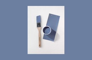 a small paintbrush and a can of blue paint rest on a white piece of paper.