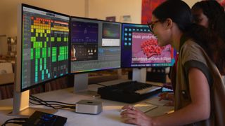 The M4 Mac mini being used by a woman to produce music on a multi-display setup.