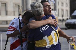 Fans of rival teams Boca Juniors, right, and River Plate, left, embrace