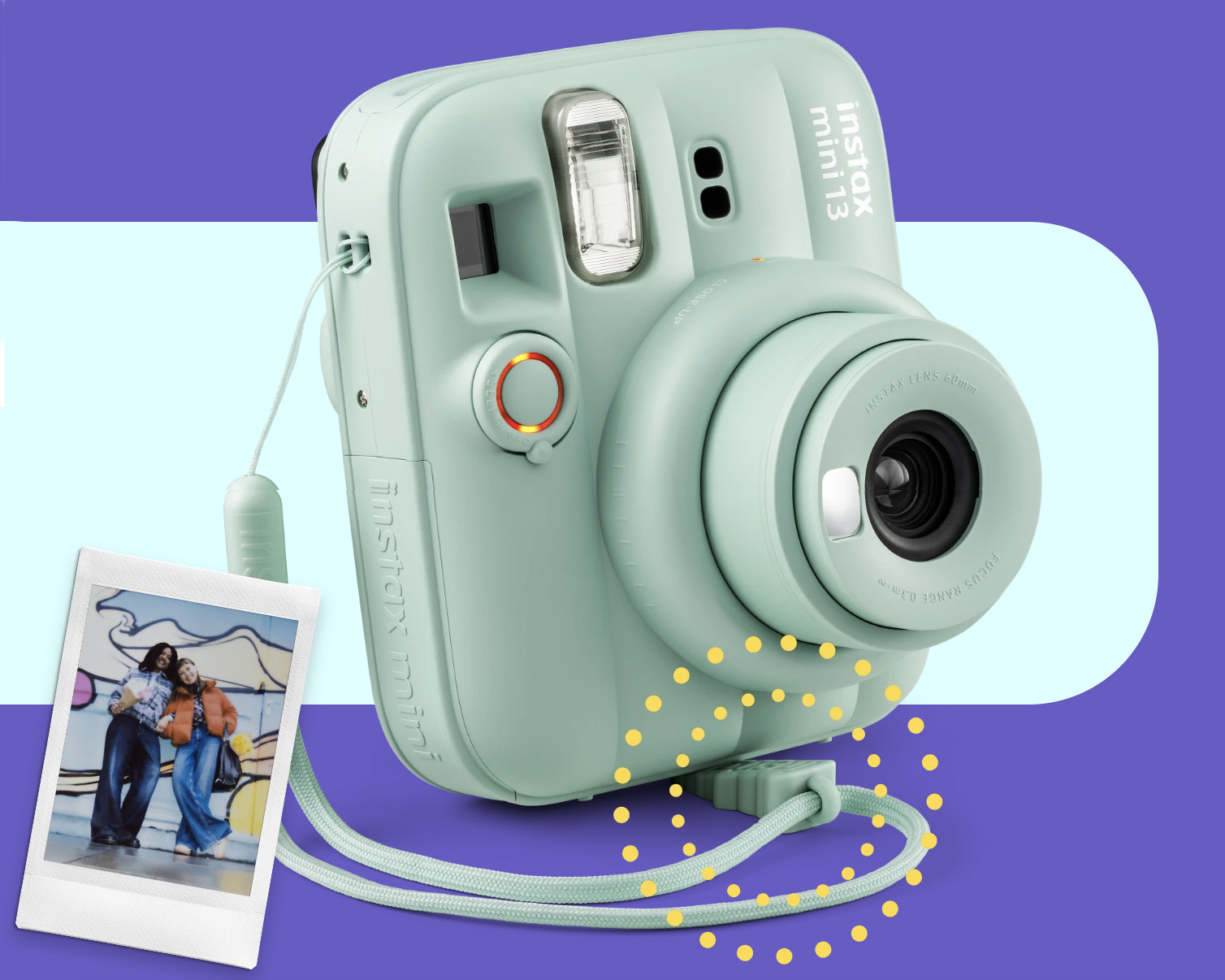 Fujifilm Instax Mini 13 in green, on a green and purple backdrop, with the strap's wedge propping it up, next to a instant print