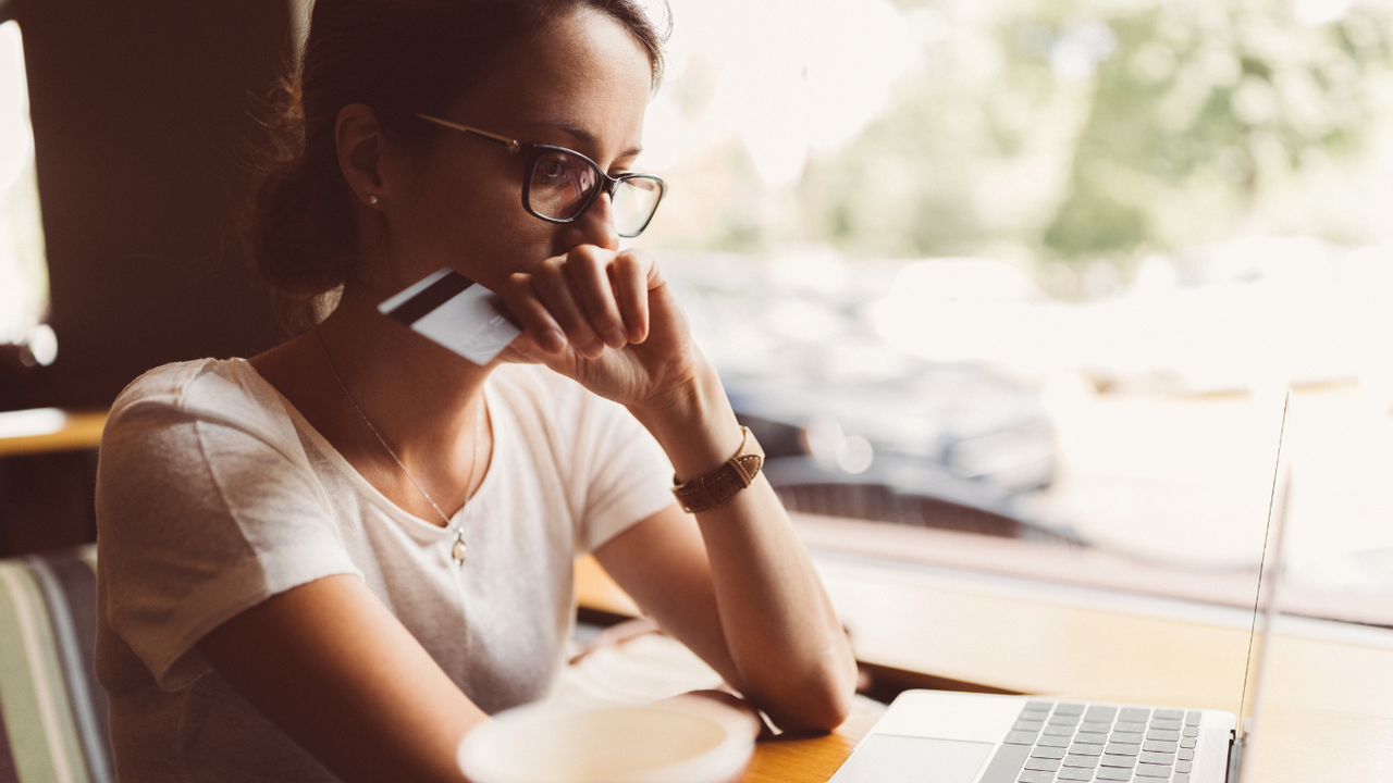 A woman holds a credit card as she looks at her computer screen