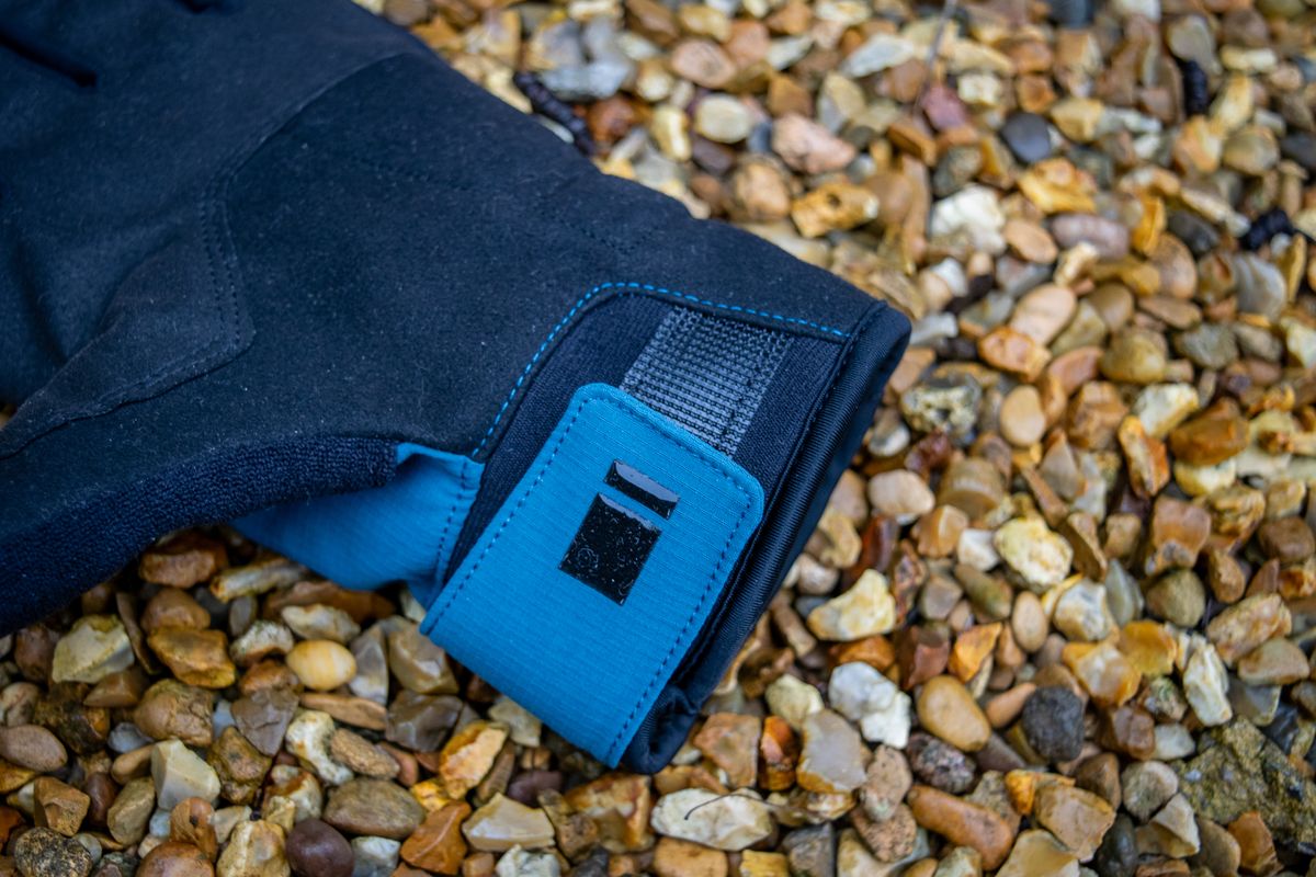 A pair of blue Madison DTE waterproof gloves on gravel