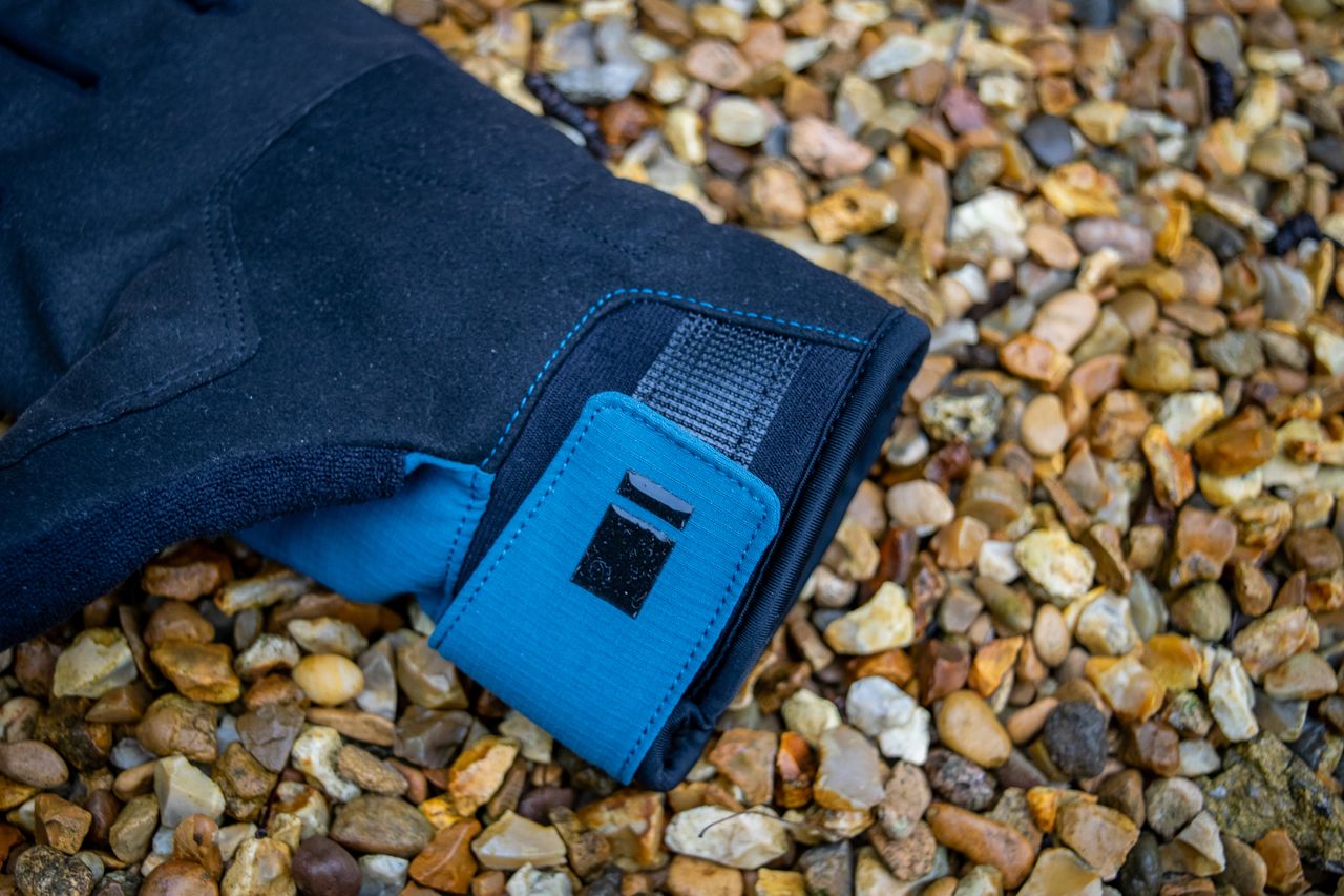 A pair of blue Madison DTE waterproof gloves on gravel