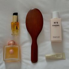 Amouage perfume laid out on a. white sheet with a hairbrush and other beauty products