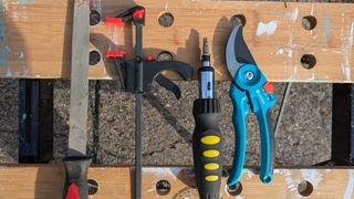 A bypass pruner with tools on a workbench