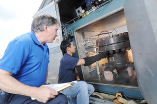 Paul Steffes and Danny Duong, both of Georgia Tech, examine the instrumentation on a machine used to simulate atmospheres on alien planets.