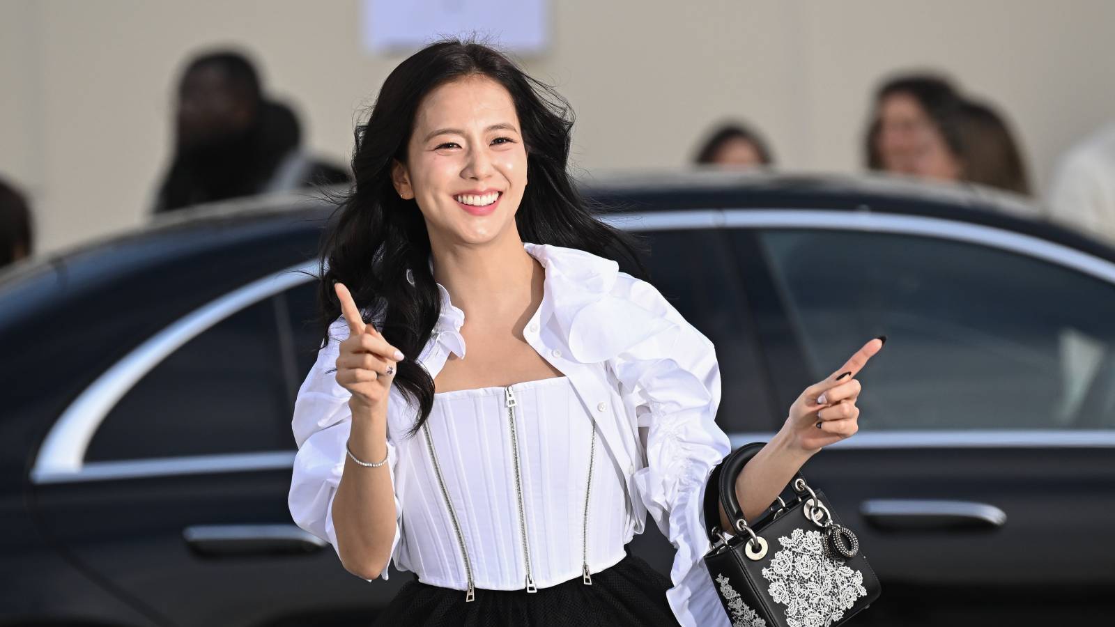 Jisoo smiling and pointing outside a car