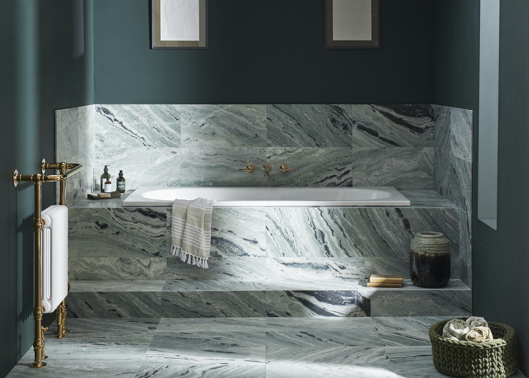 A turquoise, blue tiled bathroom with a step up bath rub in the middle as well as other bathroom essentials placed around it such as soap and body wash