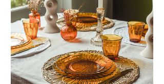 table with rattan placemats, orange glassware and ceramic accessories to show key components of the 70s inspired interior design trend