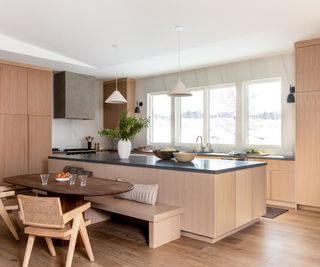 Pale wooden kitchen with marble island and gold range hood