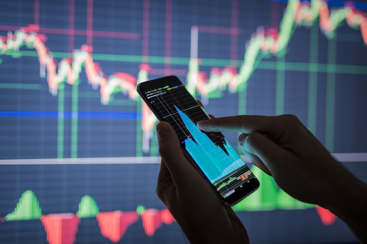 Person holds phone showing stock market data