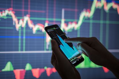Person holds phone showing stock market data