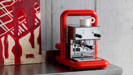 a stainless steel coffee maker wrapped in a red pip frame as modern art