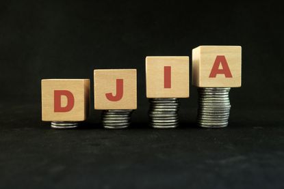 DJIA, the acronym for Dow Jones Industrial Average, spelled out on wooden blocks on ascending stacks of coins