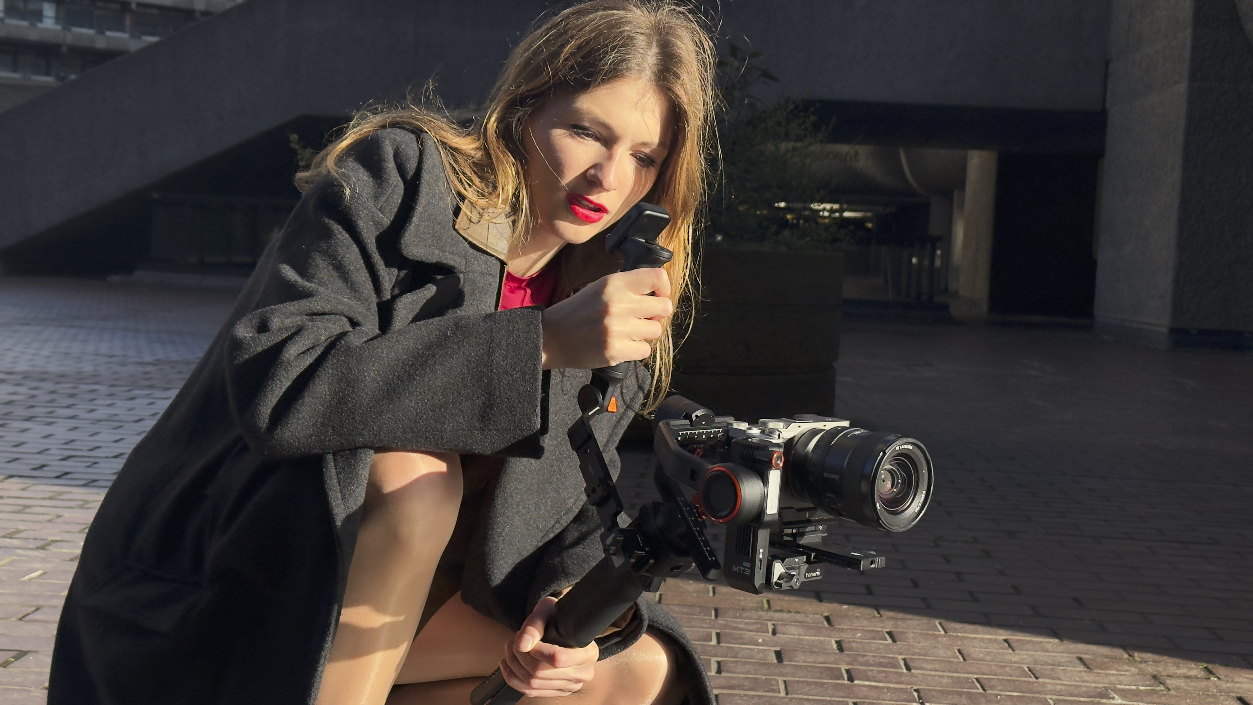 Side view of the Hohem MT3 gimbal holding a Sony mirrorless camera with lens attached, suspended from the gimbal arm.