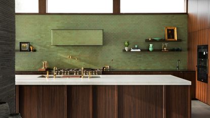A green tiled kitchen with brown wooden counters and white marbled worktops.