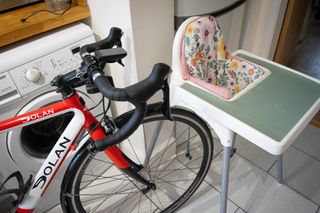 a bike in a kitchen near a baby feeding chair