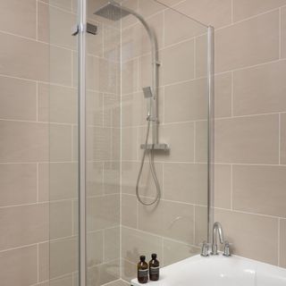 bathroom with shower and cream tiles wall