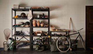 a large black shelving unit, one of our favorite garage storage ideas, full of sporting items such as golf balls, wheels, bowling balls and garden pots