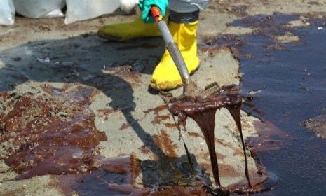 A BP cleanup crew shovels oil from a beach on May 24, 2010 at Port Fourchon, Louisiana.