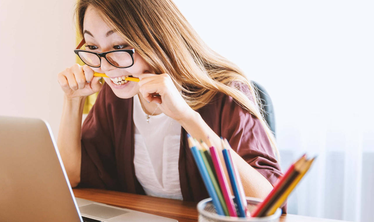 Stressed woman bites a pencil while viewing a laptop computer screen 