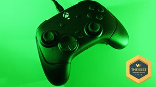 Top-down view of the black Razer Wolverine controller connected by a USB cable, illuminated under vivid green ambient lighting with 'The Best' award badge from Windows Central.