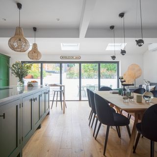 Kitchen-diner with large dining table, island with storage and bi-fold doors to the garden
