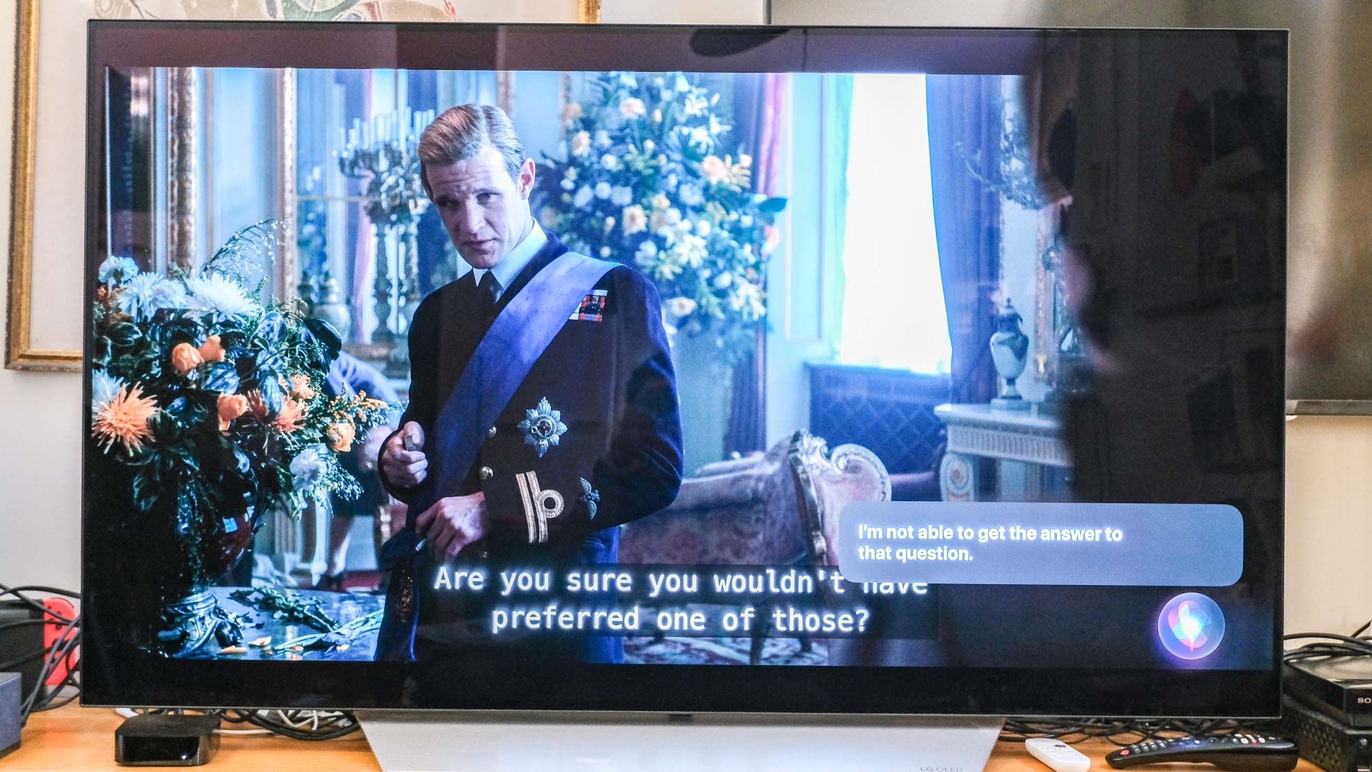 Matt Smith as Prince Philip in The Crown, appears next to a message that says "I'm not able to get the answer to that question" on a TV connected to the Apple TV 4K (2022)