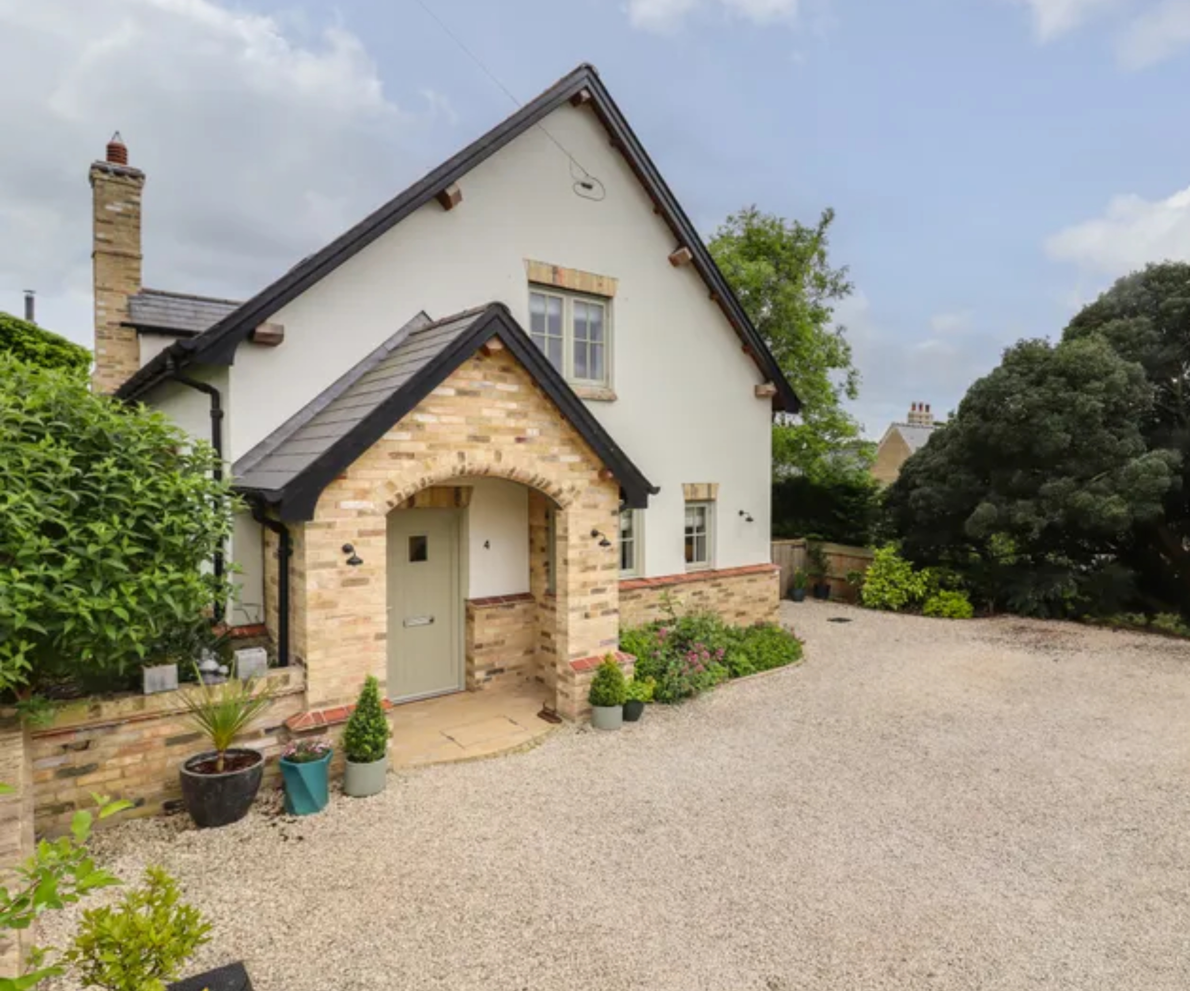 rendered and brick clad country style cottage with large gravel driveway