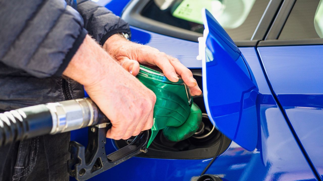 A male hand pumping gas into a car.