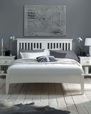 White wooden Linea Etienne king-sized bed with grey bedlinen in bedroom with grey walls and funky artwork