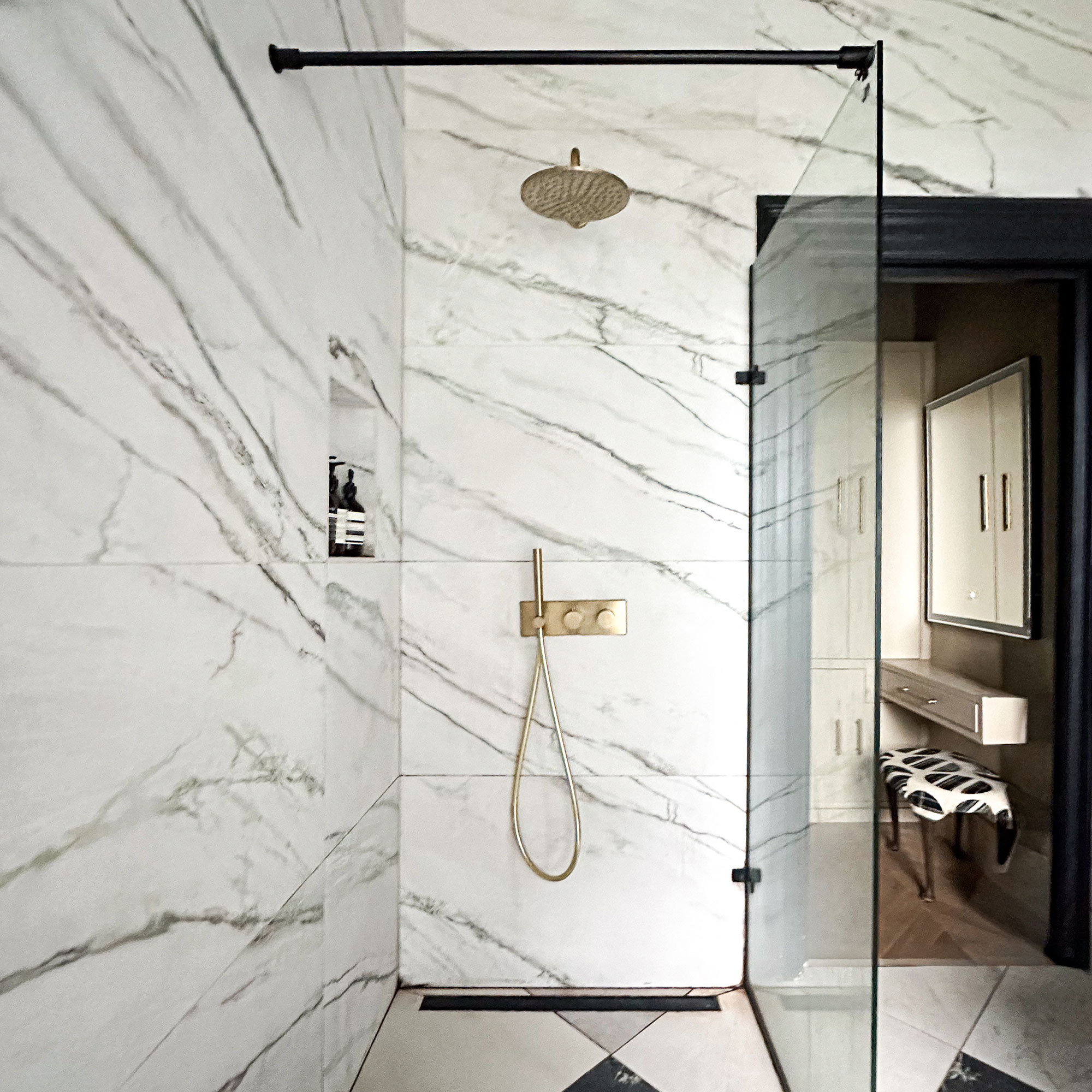 Walk-in shower with glass partition, brass hardware and marble walls and floor