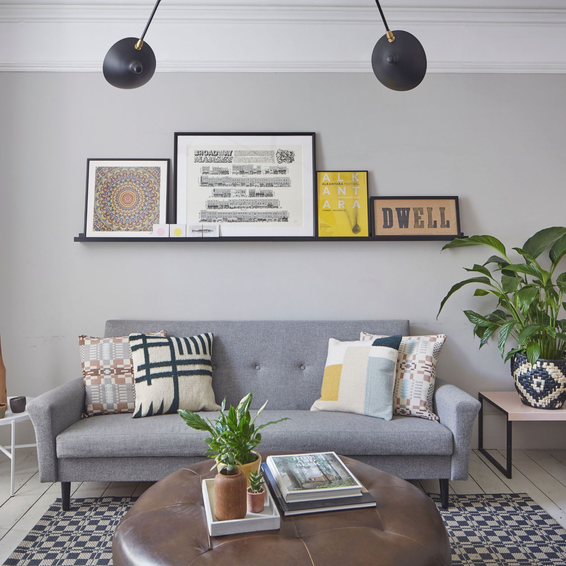 Living room decorated in a soft grey colour with grey sofa with multi-coloured cushions and large leather ottoman in the centre of the room