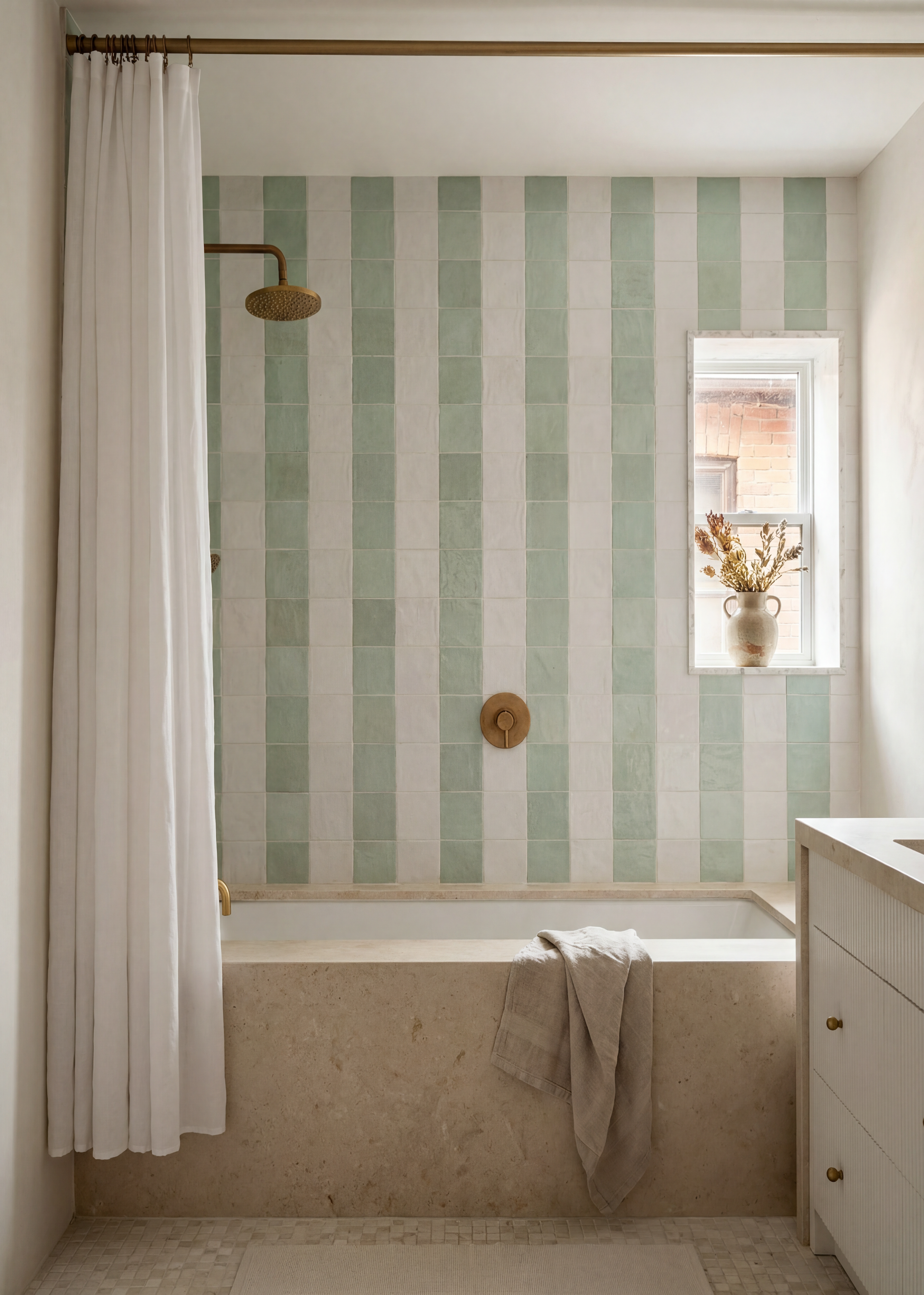 a classic modern bathroom with a built in bath and overhead shower with zellige wall tiles in mint green and off white