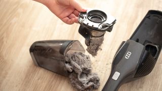 A handheld vacuum cleaner showing the dust collected in the canister and filter