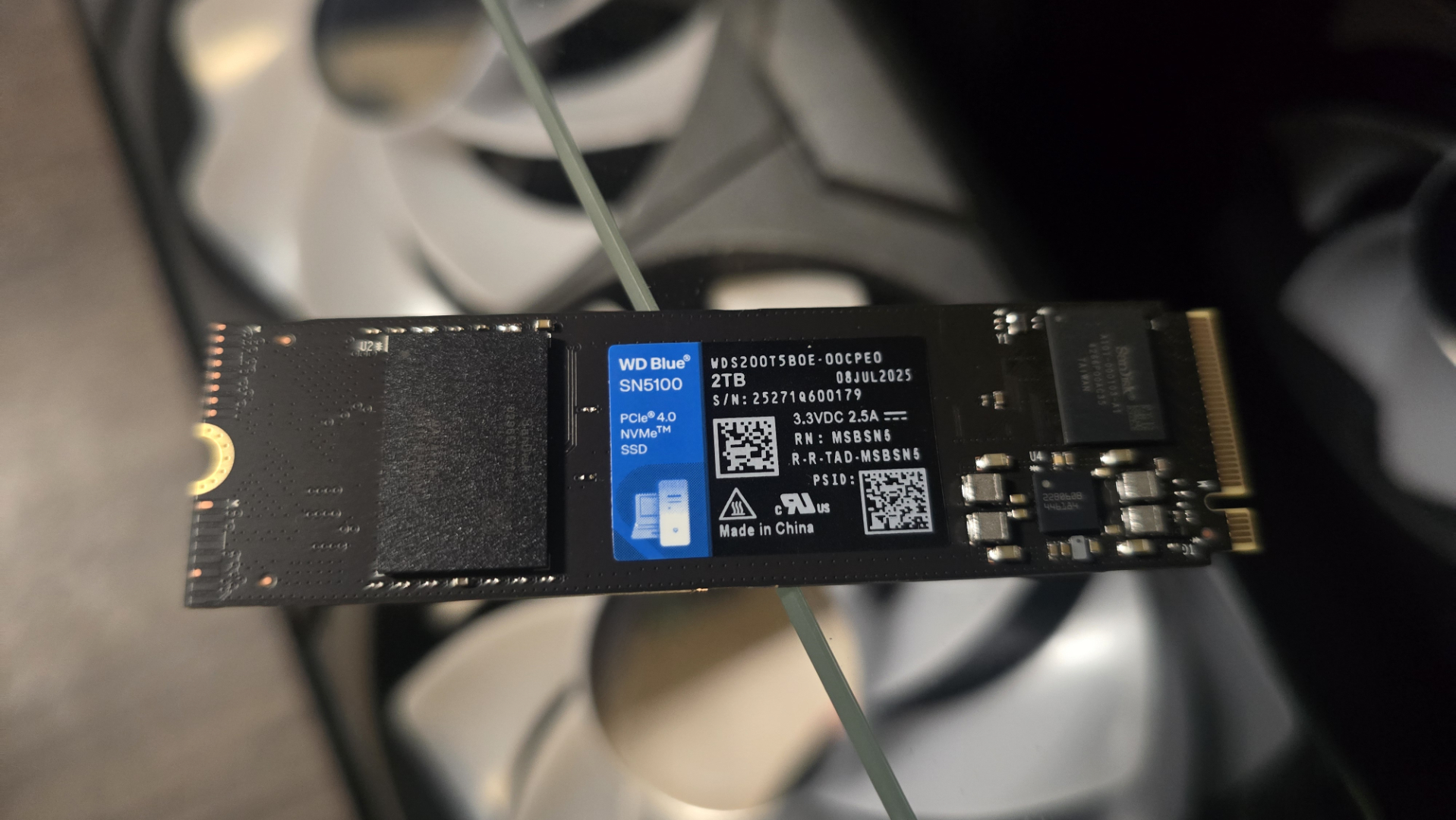 A WD Blue SN5100 ready to be installed inside a gaming PC.