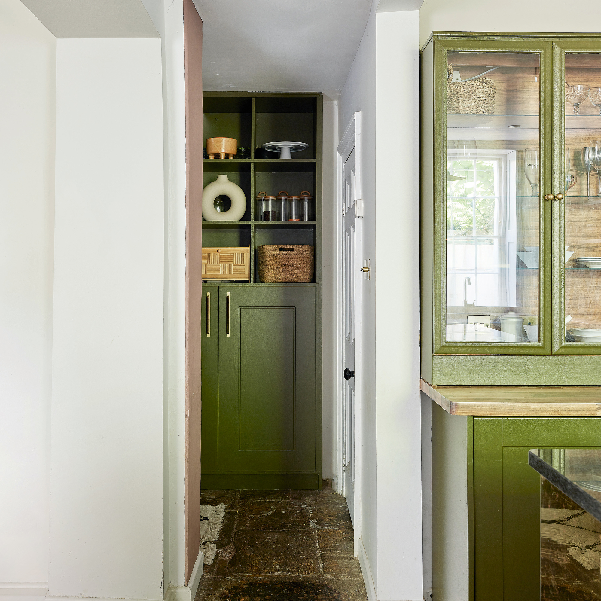 view into a utility room or boot room with green fitted cabinets with cabinets below and open shelving above