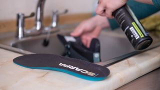 A woman cleaning hiking boots in the sink