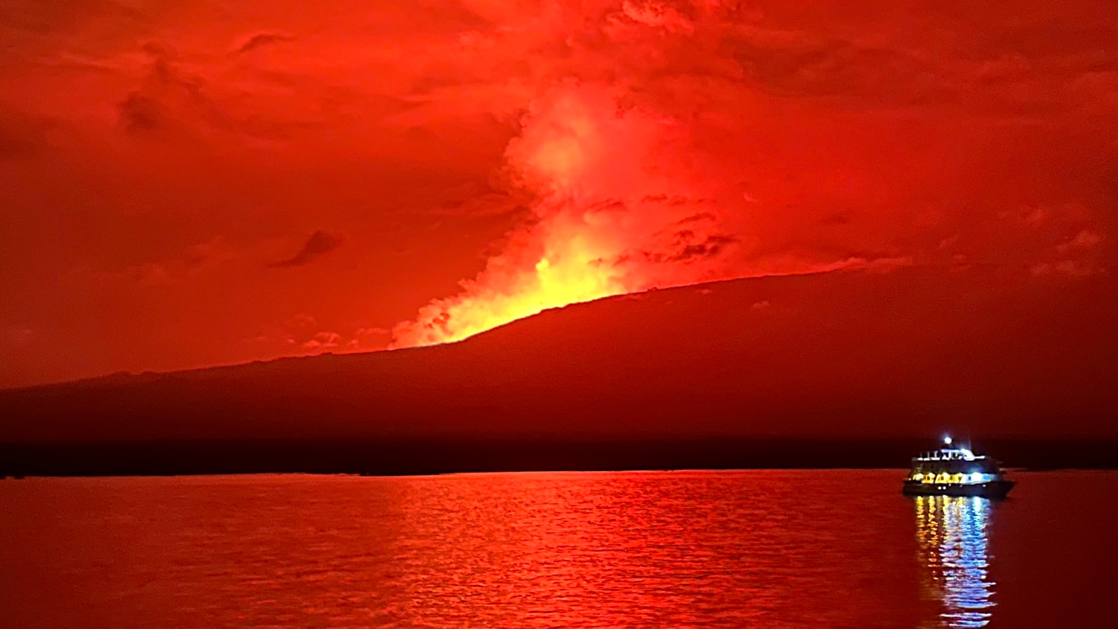 Lava glowing red in the night sky as the volcano erupts